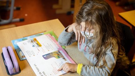 Une enfant réalise un exercice en classe en portant un masque de protection contre le Covid-19, le 3 décembre 2021 à Gand (Belgique). (JAMES ARTHUR GEKIERE / MAXPPP)