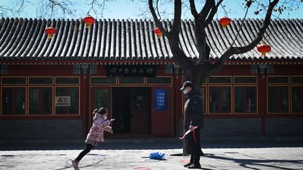 Une petite fille joue avec son père dans un parc de Pékin, le 14 mars 2020, en Chine. (WANG ZHAO / AFP)