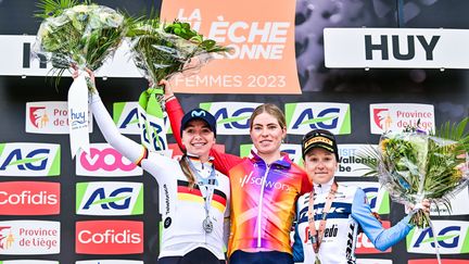 L'Allemande Liane Lippert (Movistar) et l'Italienne Gaia Realini (Trek) encadrent la grande reine des classiques cette année, la Néerlandaise Demi Vollering, victorieuse de la Flèche wallonne, le 19 avril 2023. (DIRK WAEM / AFP)