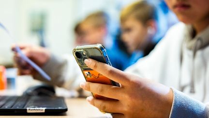 Un enfant utilise un téléphone dans une école élémentaire de Heinenoord (Pays-Bas), le 7 novembre 2023. (ANP MAG / AFP)