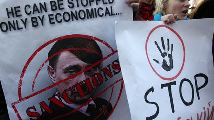 Des manifestants ukrainiens &agrave; Kiev (Ukraine), le 11 mars 2014. Leurs affiches comparent Vladimir Poutine &agrave; Adolf Hitler. (ANATOLII STEPANOV / AFP)