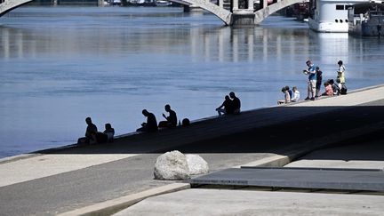 Ces Lyonnais tentent de s'abriter des rayons du soleil, lundi 17 juillet, sur les berges du Rhône. (JO?L PHILIPPON / MAXPPP)