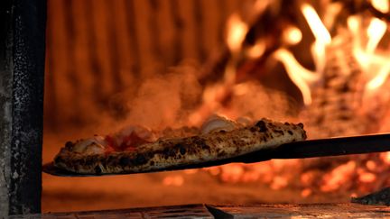 Une pizza sort d'un four à Naples (Italie), le 6 décembre 2017. (TIZIANA FABI / AFP)