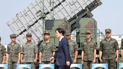 Le président taïwanais Lai Ching-te passe devant des soldats dans une base navale à la suite d'un exercice militaire chinois à Taoyuan, le 18 octobre 2024. (I-HWA CHENG / AFP)