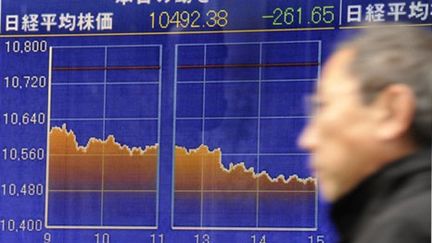 Un homme devant un panneau de cotation de la Bourse de Tokyo (AFP/Toru Yamanaka)