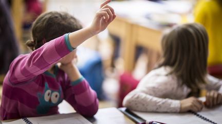 Une élève lève le doigt pour intervenir dans le cours. (FLORIAN GAERTNER / PHOTOTHEK)