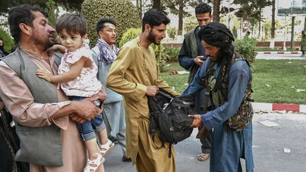 Un combattant taliban fouilles les sacs de personnes sortant de l'aéroport Hamid Karzai de Kaboul en Afghanistan. (WAKIL KOHSAR / AFP)