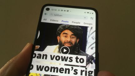 Une vidéo d'une&nbsp;conférence de presse du porte-parole des talibans, Zabihullah Mujahid, consultée sur un téléphone via&nbsp;Facebook, le 17 août 2021, à Hong Kong. (EYEPRESS NEWS / AFP)