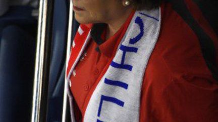 Supportrice. La présidente du Chili, Michelle Bachelet, écharpe de football au nom de son pays autour du cou, assiste au premier match de l'équipe chilienne (contre l'Australie), le 13 juin au Brésil. (JUAN BARRETO / AFP)