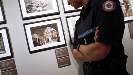 Un surveillant du Centre pénitentiaire Sud-Francilien devant des oeuvres choisies par des détenus dans le cadre de l'exposition "Le Voyage" conçue par eux.
 (THOMAS SAMSON / AFP)