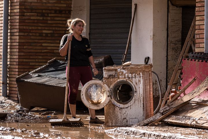 Une habitante d'Utiel, dans la Communauté valencienne (Espagne), tente de drainer la boue dans son domicile inondé, le 30 octobre 2024. (DIEGO RADAMES / AGENCE ANADOLU VIA AFP)