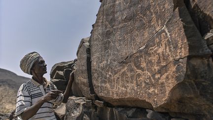 Ibrahim Dabale, 50 ans, autochtone et gardien de l'art, raconte les anciennes représentations de la faune et d'autres pratiques culturelles, caractéristiques de l'époque, gravées dans la roche volcanique sur le site d'art rupestre d'Abourma au nord de Djibouti. (TONY KARUMBA / AFP)