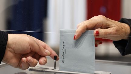 Une électrice dépose son bulletin de vote alors qu'elle vote dans un bureau de vote du Touquet, pour le deuxième tour des élections régionales françaises du 27 juin 2021. (LUDOVIC MARIN / POOL)