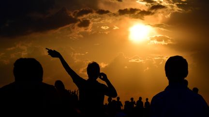 Des habitants admirent le spectacle de la plus longue éclipse du siècle à Berlin (Allemagne). (TOBIAS SCHWARZ / AFP)