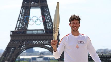 "Enchantée, madame". La flamme olympique est présentée à la Dame de fer par le champion du monde de BMX Matthias Dandoy, le 15 juillet. (EMMANUEL DUNAND / AFP)