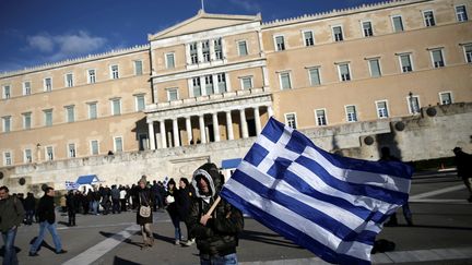 Un homme brandit un drapeau grec lors d'une manifestation contre l'austérité, à Athènes, le 14 février 2017. (ALKIS KONSTANTINIDIS / REUTERS)