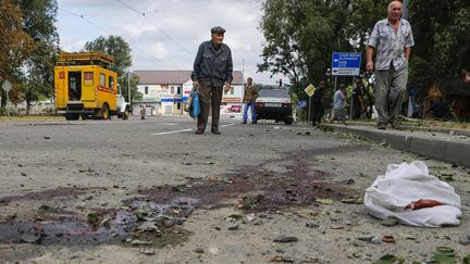 Des habitants de Donetsk&nbsp;(Ukraine) marchent dans une rue au sol t&acirc;ch&eacute; de sang, samedi 23 ao&ucirc;t 2014. (MAXIM SHEMETOV / REUTERS)