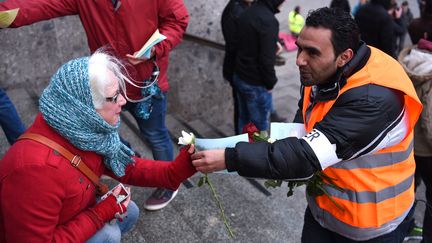 Un réfugié syrien offre des fleurs aux passants,&nbsp;en guise de manifestation&nbsp;contre les violences du Nouvel An, à Cologne (Allemagne), le 16 janvier 2016.&nbsp; (PATRIK STOLLARZ / AFP)