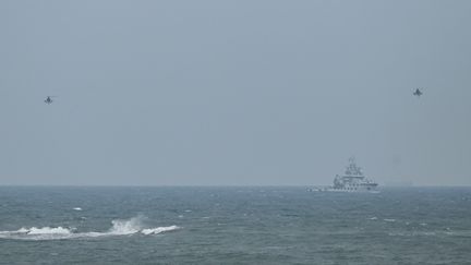 Deux hélicoptères militaires chinois survolent un remorqueur de la marine de Pékin, à proximité de l'île de Taïwan, le 7 avril 2023. (GREG BAKER / AFP)