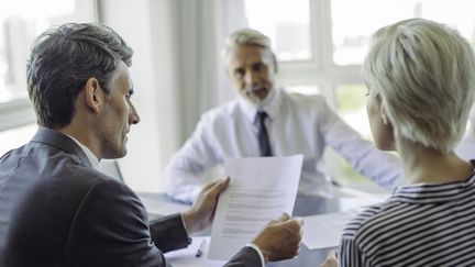 Un conseiller financier et des clients autour d'une table. (FR?D?RIC CIROU / MAXPPP)