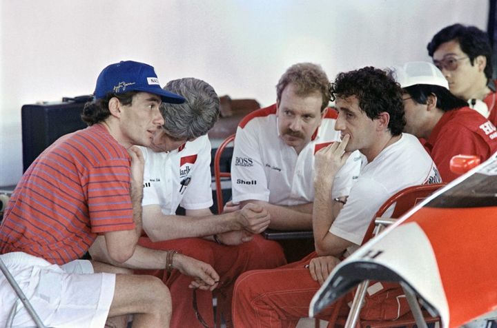 Le Brésilien Ayrton Senna et le Français Alain Prost dans les stands de l'écurie McLaren, le 18 mars 1989, avant le Grand Prix du Brésil. (ANDREW MURRAY / AFP)