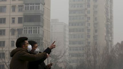 Deux hommes bravent le nuage de pollution à Pékin (Chine), le 25 décembre 2015. (KIM KYUNG HOON / REUTERS)