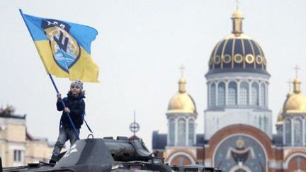 A Kiev, un enfant agite un drapeau juché sur un blindé pris aux pro-russes. (AFP/Anatoli Stepanov)