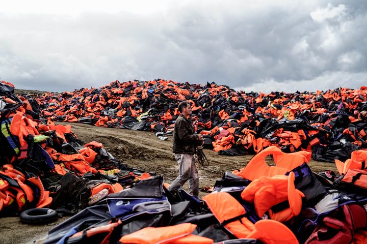 Un homme marche au milieu de gilets de sauvetage laissés par des migrants, après leur traversée de la mer Egée et leur arrivée sur l'île grecque de Lesbos (Grèce), le 27 novembre 2015. (HALIT ONUR SANDAL / NURPHOTO)