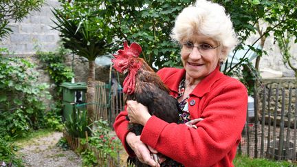 Corinne Fesseau pose avec son coq Maurice dans son jardin à&nbsp;Saint-Pierre-d'Oleron, 6 juin 2019 (XAVIER LEOTY / AFP)