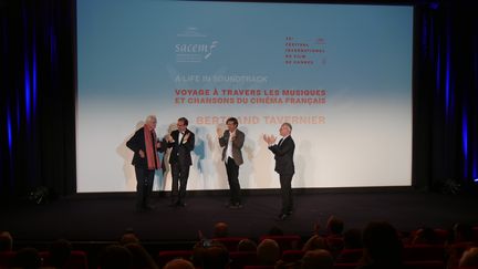 Bertrand Tavernier est applaudi par, Jean-Noël Tronc, directeur général de la Sacem, Stéphane Lerouge, Thierry Frémaux, délégué général du Festtival de Cannes. (Lorenzo Ciavarini Azzi/franceinfo Culture)