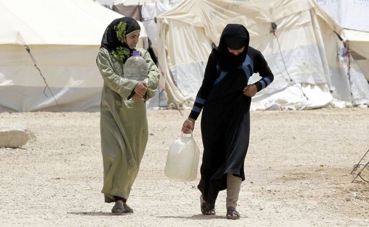 Deux r&eacute;fugi&eacute;s syriennes portent de l'eau, dans le camp de Zaatari, en Jordanie, le 18 mai 2013. (KHALIL MAZRAAWI / AFP)