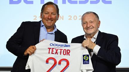 L'homme d'affaires américain John Textor (à gauche) ) et Le président du club de football de Lyon Jean-Michel Aulas (à droite) et posent à l'issue d'une conférence de presse pour annoncer la vente d'une participation importante du club à Textor's Eagle Football Holdings, à Decines-Charpieu, près de Lyon, le 21 juin 2022. (OLIVIER CHASSIGNOLE / AFP)