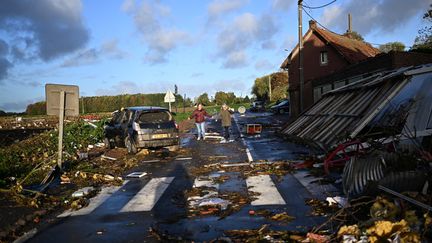 Des habitants de Bihucourt (Pas-de-Calais) marchent à travers les débrits&nbsp;de bâtiments détruits après le passage d'une tornade, lundi 24 octobre 2022. (SAMEER AL-DOUMY / AFP)