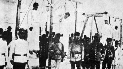 Des officiers ottomans posent devant des Arm&eacute;niens pendus en place publique &agrave; Alep (Syrie), en 1915. (AFP)