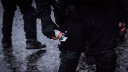 Un officier de police tient une grenade explosive GLI-F4 dans la main lors d'une manifestation de "gilets jaunes" à Paris, le 26 janvier 2019, sur la place de la Bastille. (KARINE PIERRE / HANS LUCAS)