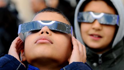 Deux enfants regardent une &eacute;clipse partielle de Soleil, le 4 janvier 2011, &agrave; Tunis (Tunisie). (FETHI BELAID / AFP)