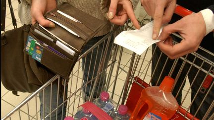 Un couple v&eacute;rifie sont ticket de caisse &agrave; la sortie d'un supermarch&eacute;, en d&eacute;cembre 2005. (FLORENCE DURAND / SIPA)