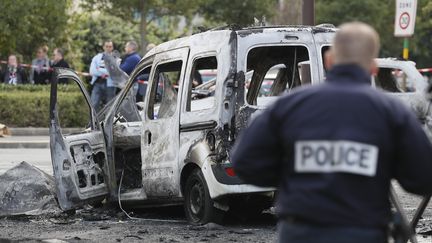 Les voitures de police ont été visées par des cocktails Molotov, lancés par une vingtaine d'assaillants. (THOMAS SAMSON / AFP)