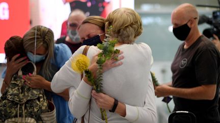 Des familles se retrouvent le&nbsp;1er novembre 2021 à l'aéroport de Sydney (Australie). (SAEED KHAN / AFP)