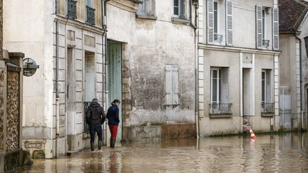 Des habitants dans une rue inondée de Crécy-la-Chapelle (Seine-et-Marne), le 10 octobre 2024. (YOAN VALAT / EPA)