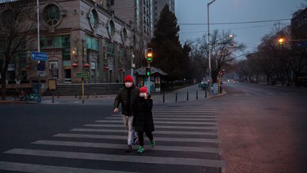 Un couple&nbsp;marche dans une rue de Pékin le 28 janvier 2020.&nbsp; (NICOLAS ASFOURI / AFP)