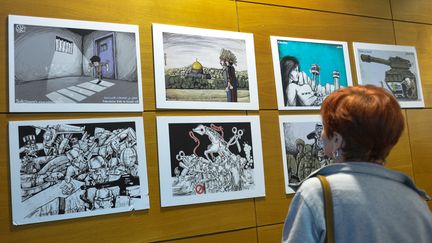 Une femme assiste à une expostion montrant le travail du dessinateur de presse palestinien Mohammad Sabaaneh, à Dublin, en Irlande, le 29 mars 2019.&nbsp; (ARTUR WIDAK / NURPHOTO /¨AFP)