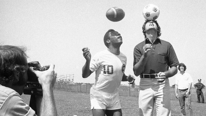 Le footballeur Pelé, alors au New York Cosmos, et le quarterback des New York Jets Joe Namath échangent les&nbsp;ballons de leurs sports respectifs, à New York, le 5 août 1975. (RAY HOWARD/AP/SIPA / AP)