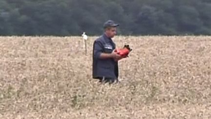 &nbsp; (Un secouriste transporte une des boites noires sur le site du crash du vol MH17. © REUTERS/Reuters TV)