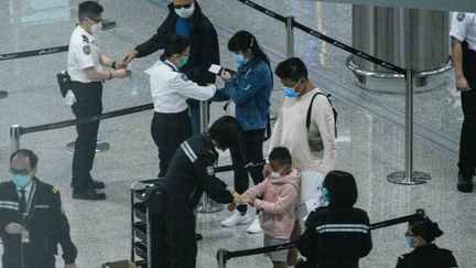 Des passagers en provenance de l'étrangers reçoivent leur bracelet de suivi de quarantaine à leur arrivée en Chine (photo d'illustration). (ANTHONY WALLACE / AFP)