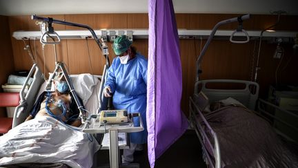 Une infirmière au chevet d'un patient positif au Covid-19, le 22 octobre 2020 à Gonesse (Val-d'Oise). (CHRISTOPHE ARCHAMBAULT / AFP)