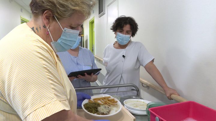 Véronique Neves, dietician at Mauriac hospital (facing front in white coat), "examine" the contents of the patients' plates after the meal is finished.  (L. Ribes / / France Televisions)