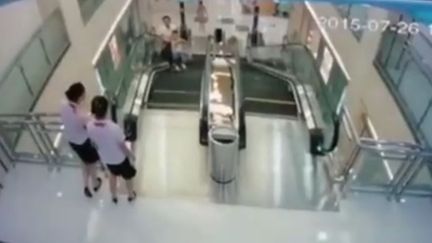 Capture d'&eacute;cran de la vid&eacute;o montrant une femme happ&eacute;e par un m&eacute;canisme d'escalator apr&egrave;s avoir sauv&eacute; son fils, &agrave;&nbsp;Jingzhou (Chine), le 25 juillet 2015. (IMAGINECHINA / AFP)