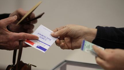 Une &eacute;lectrice pr&eacute;sente sa carte &eacute;lectorale, le 29 mars 2015 au Grand-Quevilly (Seine-Maritime). (CHARLY TRIBALLEAU / AFP)