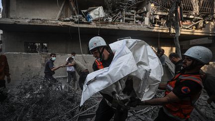 Civil protection members and residents evacuate residents from a building bombed by the Israeli army, in the town of Khan Younes in the Gaza Strip, October 14, 2023. (MUSTAFA HASSONA / ANADOLU / AFP)